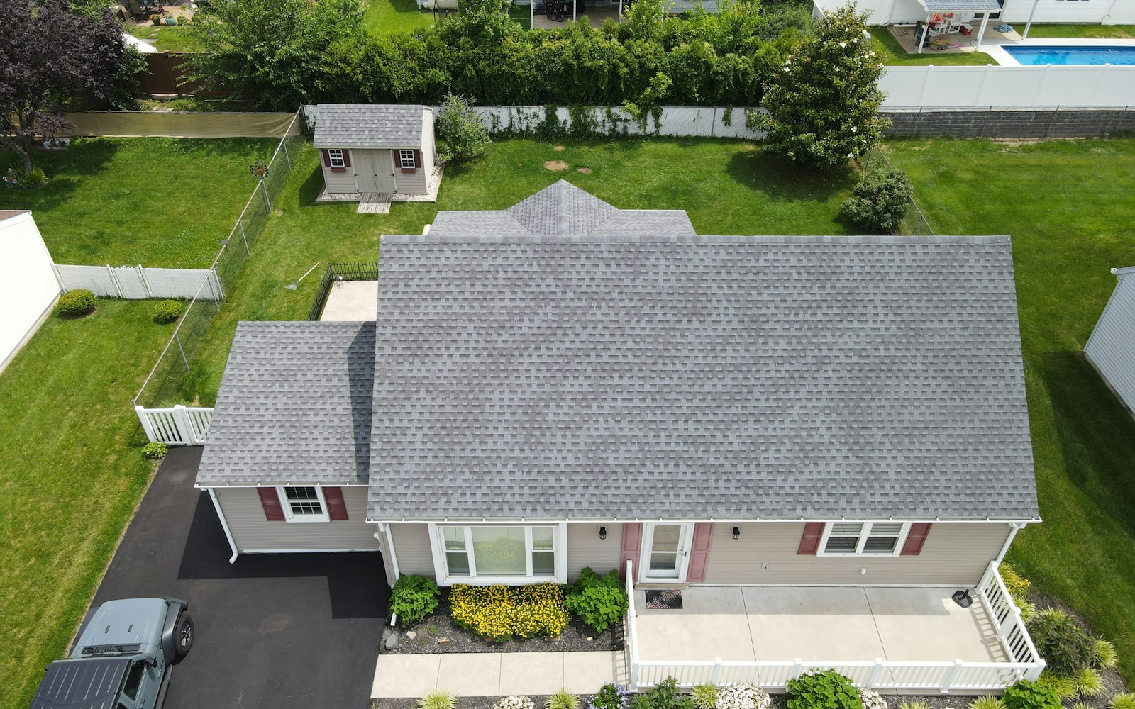 Daylight drone aerial of a residential shingle roof showing ridges, valleys, flashing lines, and gutters